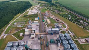 enorm industriell växt med fungerar lokal och hiss tankar som väl som de där under konstruktion. silo cisterner omgiven med vägar och järnvägar. topp se. natur bakgrund. video