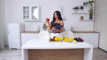 Calories counting and diet composition. Fit lady stands in front of a table with fruit and vegetables and creates healthy diet schedule. video
