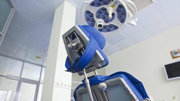 Folding chair with different appliances standing under the powerful lamp in dentist's cabinet. Close up. Low angle view. Blurred backdrop. video