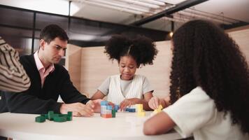 grupp av raser studenter och lärare spelar matematisk pussel roligt spel på tabeller tillsammans, kreativt inlärning i primär klass, barn utmaning för visdom på elementärt internationell skola. video
