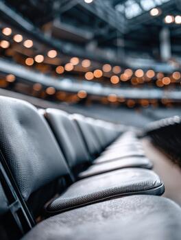 Long row of empty black seats in a large indoor arena during event setup photo