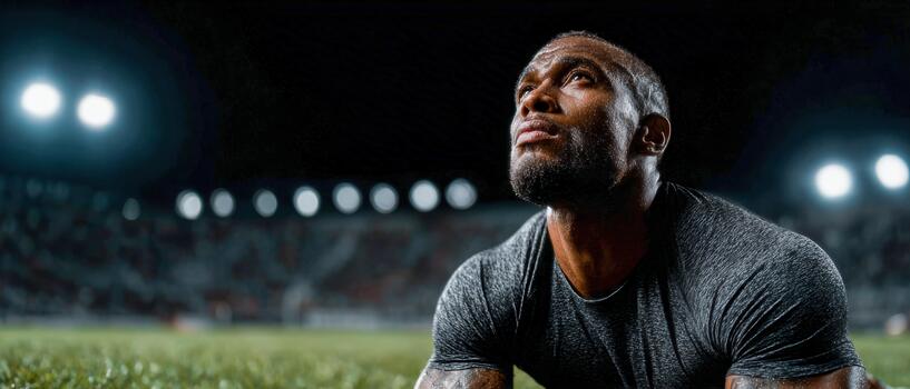 Athlete resting on the field after intense training under stadium lights photo