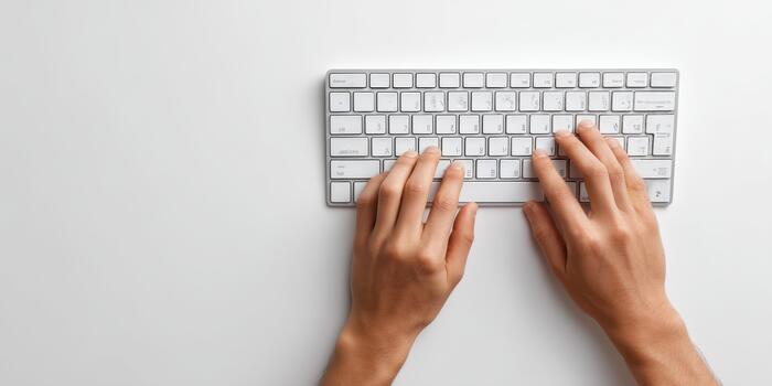 Hands typing on computer keyboard at white desk photo