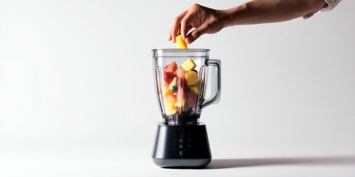 Hand adding fresh fruit to blender for smoothie photo