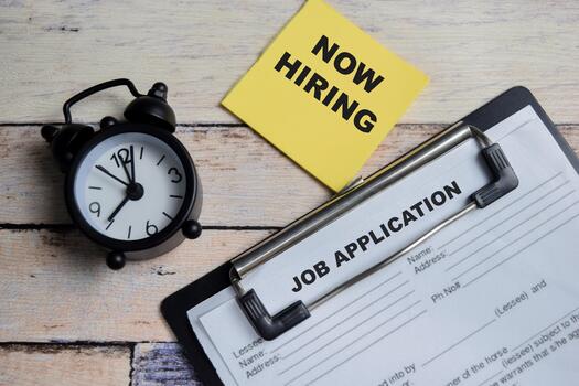 Concept of now hiring and job application write on clipboard isolated on Wooden Table. photo