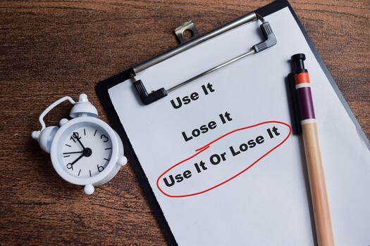 Concept of use it or lose it red circle write on clipboard isolated on Wooden Table. photo
