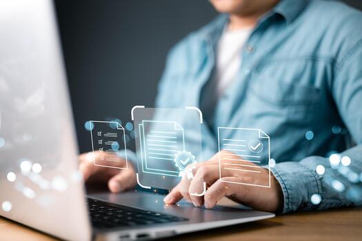person work on a laptop by floating digital documents featuring verification symbols, a certificate badge, and checkmarks, highlighting authenticity, transparency, and digital leader credibility. photo