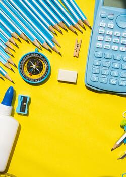 Minimal back to school background with stationery on edges and empty yellow center for text. Flat lay template for education or design projects photo