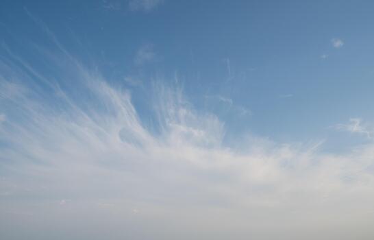 Blue sky with scattered white cirrus clouds. The clouds vary in size and shape, creating a serene atmosphere. Background light blue.. photo