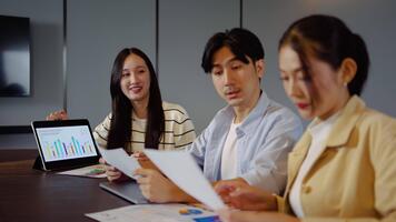 grupp av asiatisk motiverad yrkesverksamma engagerar i en strategisk möte, diskuterar företag tillväxt och uppkopplad strategier. de använda sig av tabletter och presentation till förbättra samarbete och aning delning video