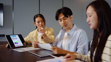 grupp av asiatisk motiverad yrkesverksamma engagerar i en strategisk möte, diskuterar företag tillväxt och uppkopplad strategier. de använda sig av läsplatta och presentationer till förbättra samarbete och aning delning video