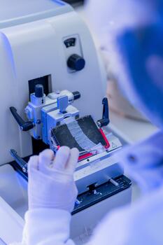 Scientist operating a precision slicing machine for material analysis in a laboratory photo