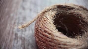 Slow motion macro close-up moving left across the textured edge of a burlap rope spool on a rustic tabletop video