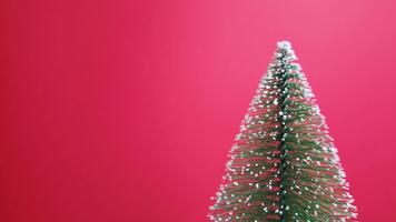 roterande miniatyr- jul träd på en statisk ram med rena röd kopia Plats, perfekt för festlig bakgrunder och design layouter video