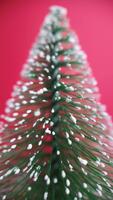 Rotating miniature Christmas tree filmed with a macro lens on a red background, perfect as a festive vertical backdrop for reels and holiday content video