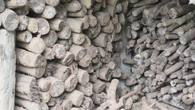 close-up, full-frame view of two tightly packed stacks of dry, weathered firewood logs and branches, with the wood exhibiting a uniform gray-brown color and visible cross-section textures. photo