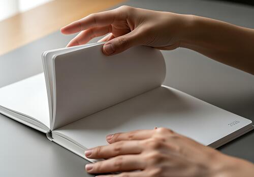 Hand turning pages of a blank notebook on a table. photo