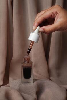 A Glad2Glow serum with its lid opened is placed on a brown fabric, creating a warm and inviting look photo