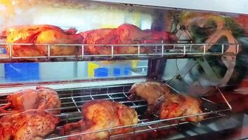 kyckling varelse rostad använder sig av ett automatisk rullande stekare. detta maskin långsamt roterar de kyckling fram tills den är jämnt kokta video