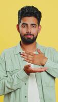 avoir besoin certains plus, S'il vous plaît donner moi. Indien homme montrant une peu bit geste avec sceptique sourire montrant le minimum signe, mesure petit taille, mendicité aider. arabe gars isolé sur Jaune studio Contexte video