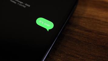 detailopname visie van een smartphone scherm tonen een uitgaand zijn over- breken omhoog thema tekst bericht in een groen bubbel net zo het verzendt. video