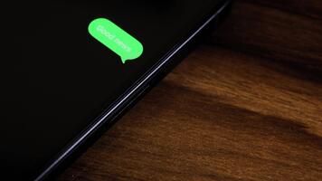 närbild se av en smartphone skärm som visar ett utgående Bra Nyheter text meddelande i en grön bubbla, fångad som den skickar med en slät dyka upp animation. video