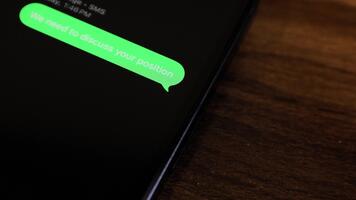närbild se av en smartphone skärm som visar ett utgående vi behöver till diskutera din placera, din prestanda har inte förbättrad, snälla du träffa mig i kontor text meddelande i en grön bubbla video