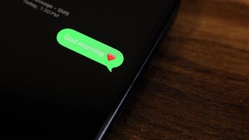 närbild se av en smartphone skärm som visar ett utgående Bra morgon- text meddelande i en grön bubbla, fångad som den skickar med en slät dyka upp animation. video