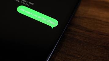 närbild se av en smartphone skärm som visar ett utgående vi behöver du på de kontor, där är ett problem med de Rapportera, snälla du ring upp tillbaka brådskande. text meddelande i en grön bubbla, fångad som den skickar. video