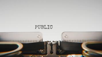 Old mechanical typewriter typing Public Interest in a close up view, with metal letters striking the white paper. video