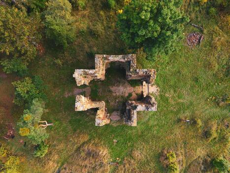 Aerial view of the ruins of the Chapel of the Exaltation of the Holy Cross in Bristev. Surrounded by nature, the remains feature stone walls and a cross-shaped layout. photo