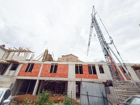 Partially constructed building with exposed red bricks and concrete frame. Urban development scene showing structural elements and ongoing work. photo