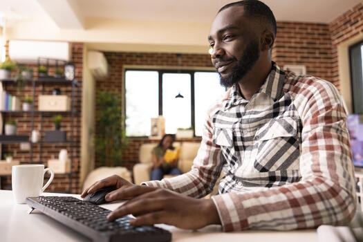 African American man typing on computer keyboard and updating his online journal and researching business strategies. Male blogger working from home on content and project presentations. photo