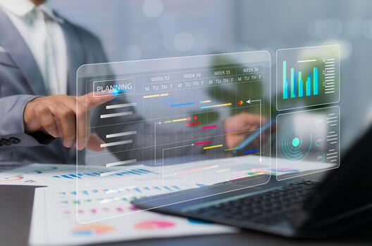 Management concept of planning and executing schedule to track progress by analyzing graphs and virtual documents. Businessman working at desk with laptop device. photo