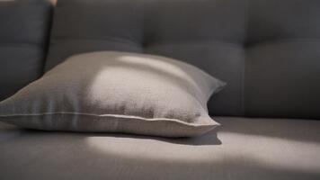 bekväm grå kudde vilar på en modern soffa med mjuk naturlig ljus skapande en mysigt avkopplande atmosfär och highlighting slät tyg textur i en lugna samtida interiör video