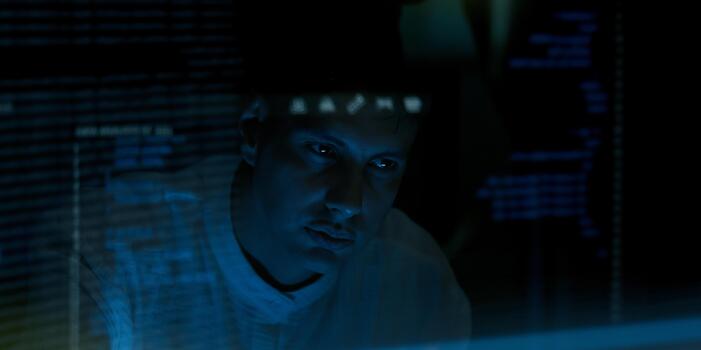 Programmer or Developer working in dark room with computer code reflected on their monitor. photo