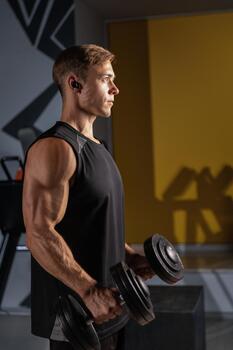 Man performs hammer curls with dumbbells in a modern gym setting during a workout session photo