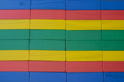 Close-up of a wall made from brightly colored wooden toy blocks arranged in a neat geometric pattern and texture, suitable for a background photo