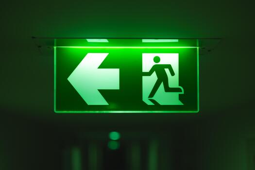 Exit way arrow direction guidance sign green color light emergency exit sign in a dark room photo