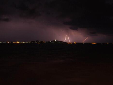 Lightning strikes over the ocean and a small island photo