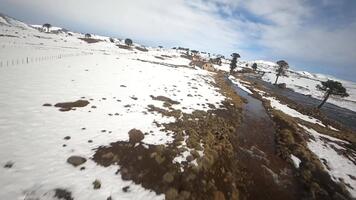 A view of a snowy mountain side with a stream running through it video