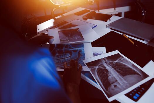 A person sitting at a desk with a computer and x - ray photo