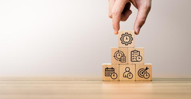 Time management and productivity concept with hand arranging wooden blocks stacked in pyramid structure, featuring icons of clock, checklist, calendar, target and workflow for planning, organization photo
