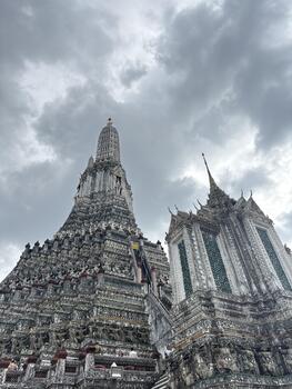 Intricate Architecture of Wat Arun Temple in Bangkok Under Dramatic Cloudy Sky Displaying Stunning Thai Design Elements photo