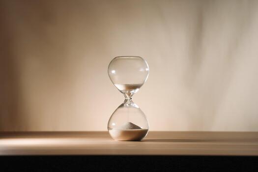 A simple hourglass on a wooden table with a beige backdrop, symbolizing time flow and minimalistic living. Running out of time, uncluttered presentation for stylish concepts u photo