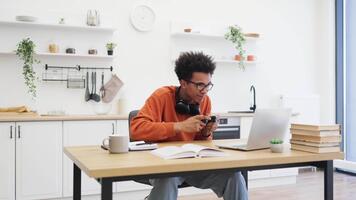 en ung man med glasögon firar en vinna medan spelar spel på Hem, innehav en kontroller. video