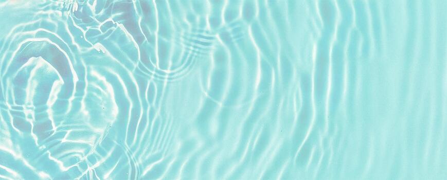 Close-up view of clear turquoise water with gentle ripples and sunlight reflections forming smooth wave patterns. Ideal for spa, nature, or relaxation background and aquatic design themes. photo