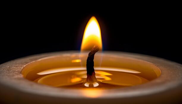 Close Up of Burning Candle Flame on Warm Wax Surface with Dark Background photo