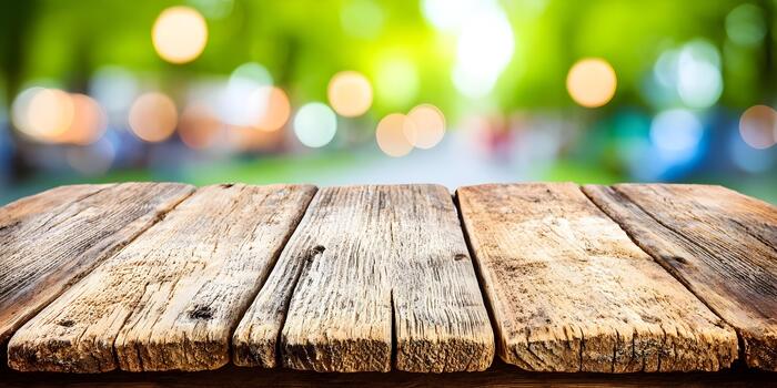 Empty rustic wooden table surface with a blurred green nature background and warm bokeh lights photo