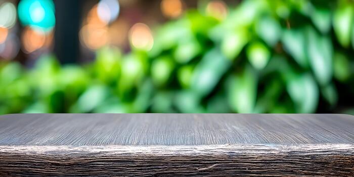 An empty rustic wooden table surface is positioned against a blurred green foliage and bokeh lights background photo